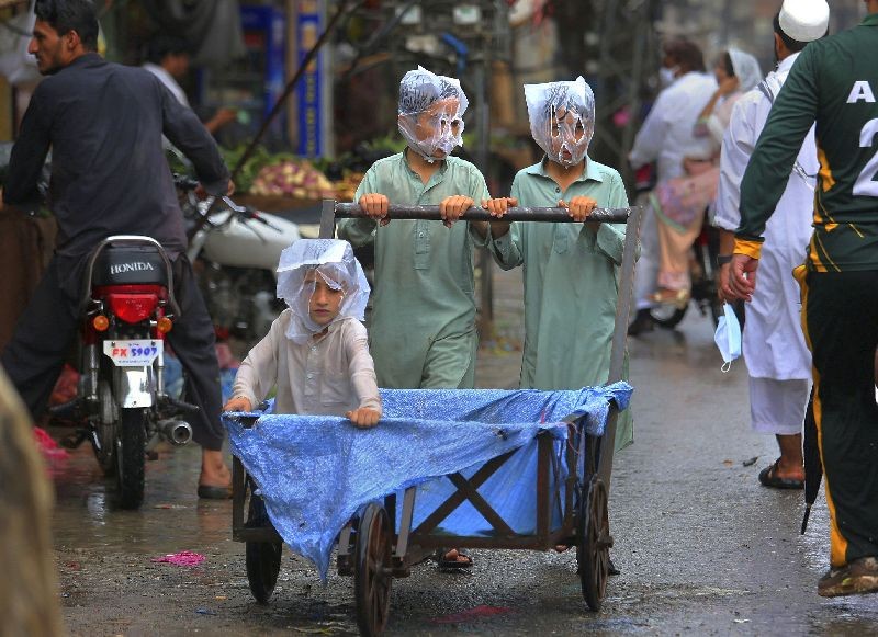Youths cover their faces with plastic bags while pushing a handcart during rainfall in Peshawar, Pakistan. (Photo by Muhammad Sajjad/AP Photo)